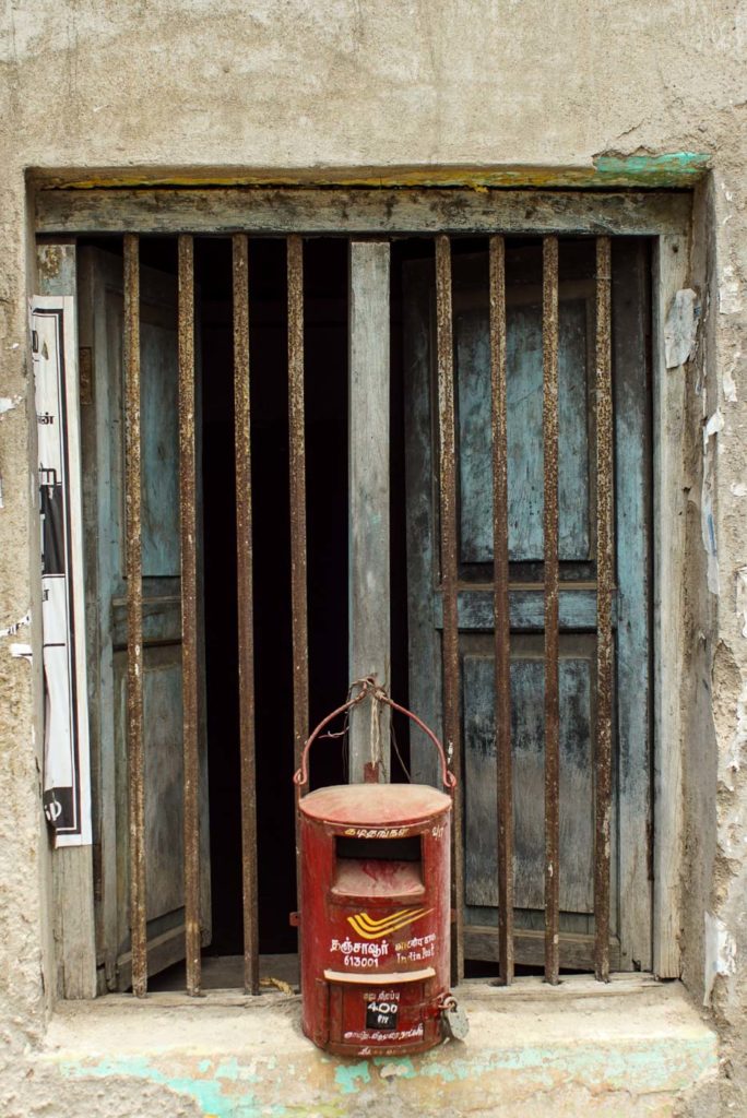 Briefkasten hinter Gitterfenster in Indien. Ein roter Briefkasten
