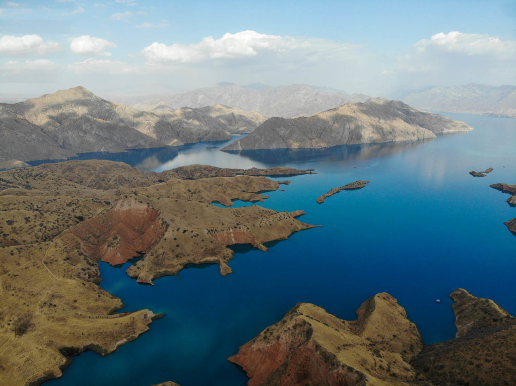 braune gebirgsformationen kommen aus kräftigblauen wasser und steigen empor. hellblauer himmel in tadschikistan