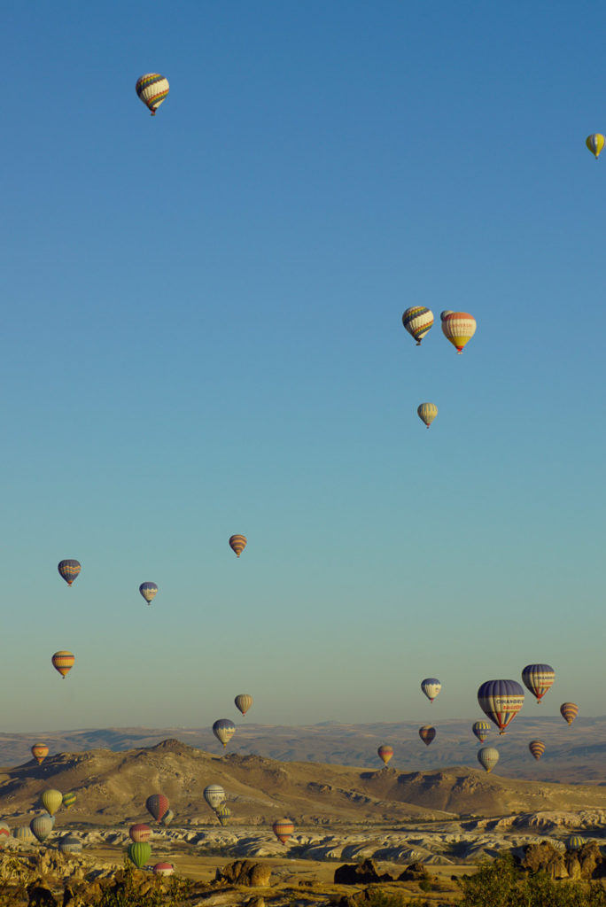 Unzählige Heißluftballons fliegen im Sonnen aufgang über den Bergen von Kappadockien. die Ballons sind verschiedenfarbig, der Himmel ist hellblau